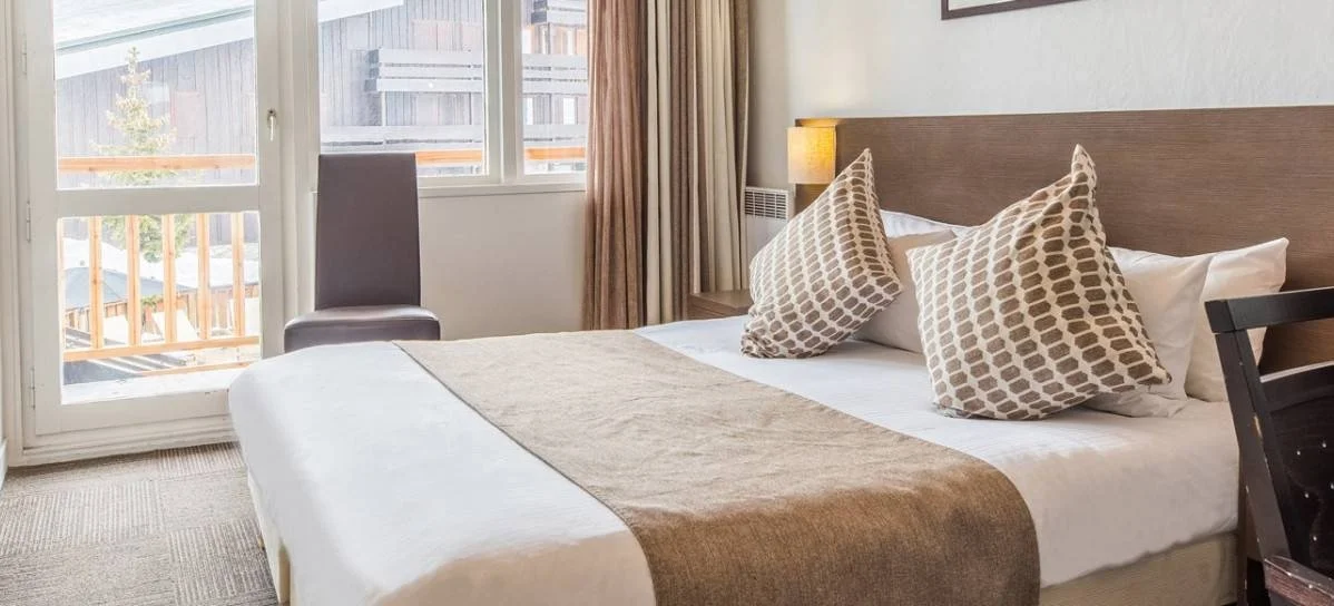Plush double bedroom at Hotel Le Mottaret in Meribel. Light modern interiors with plenty of natural sunlight.