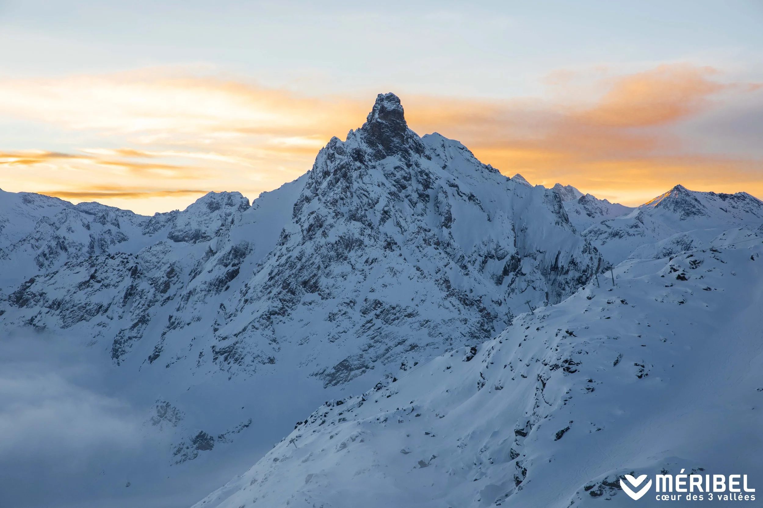 Sunrise peaks above the mountain tops. The fresh snow covers them.
