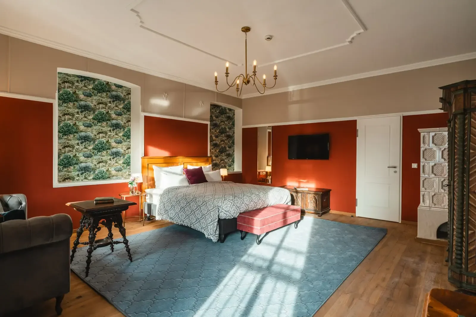 Sunlit large double bedroom with a blue rug, red walls and a lovely luxury décor.