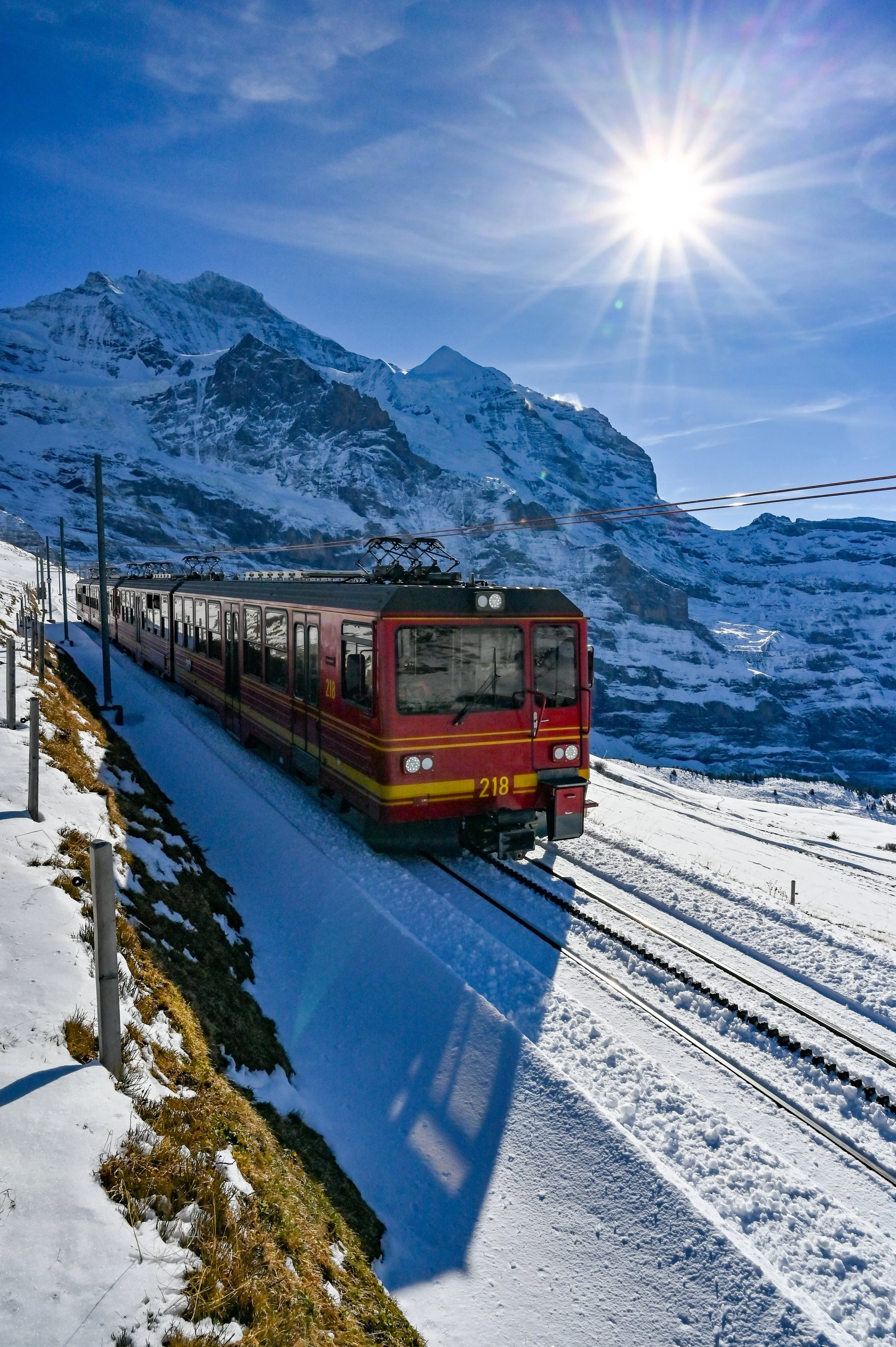 Jungfrau train soaring through the mountain railway tracks on a sunny day.