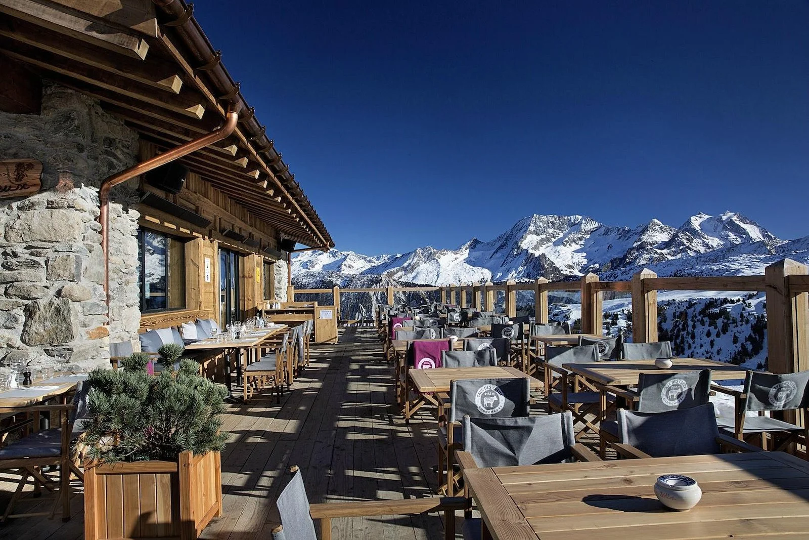 Cave des creux, Courchevel terrace with mountainous background on a clear-skies-day.