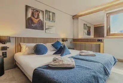 Large double room with blue bedding and plenty of backlighting to create a naturally lit space.