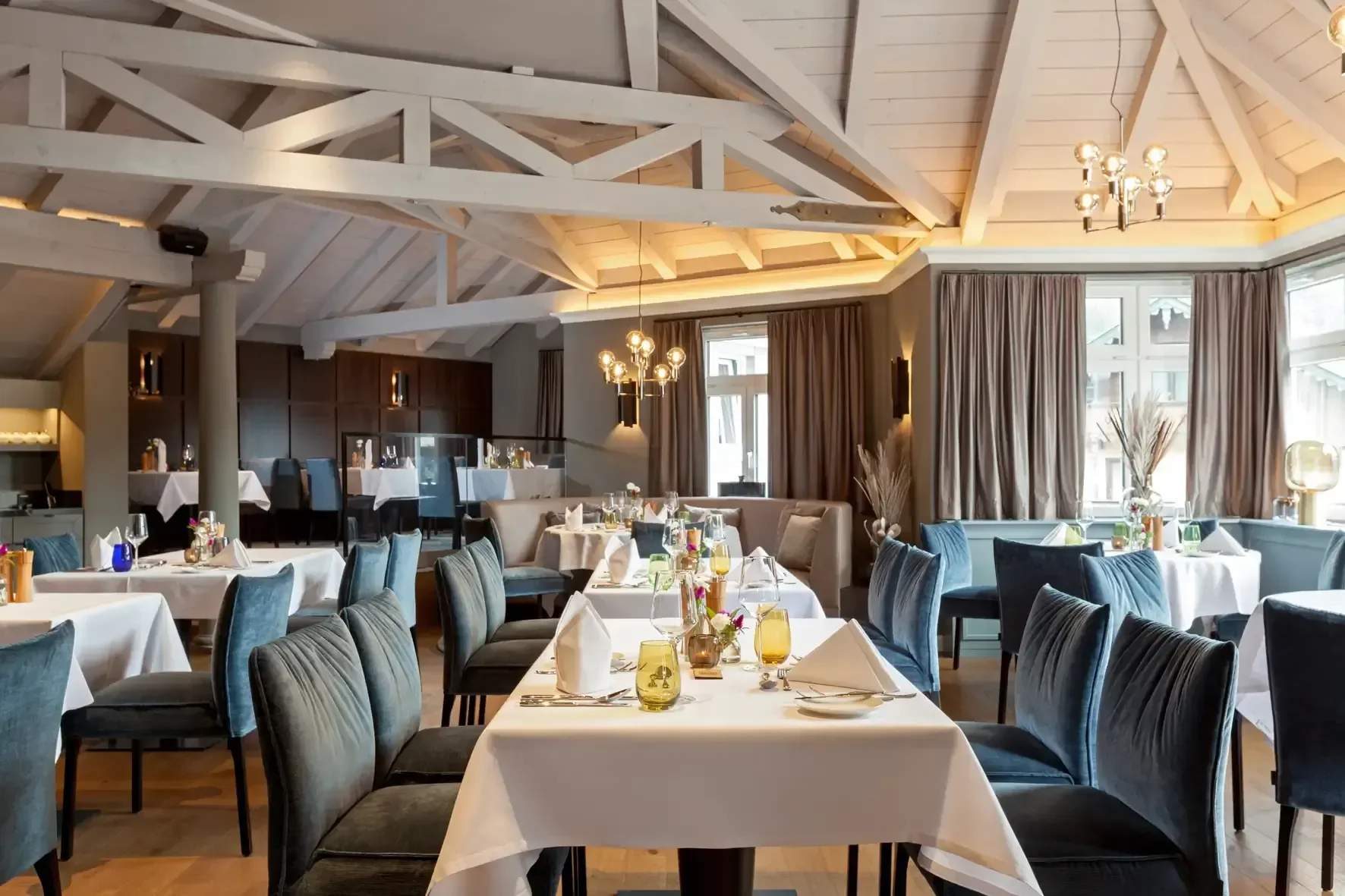 Well light dining area with plenty of tables and chairs. Calm setting with glasses and napkins. Wooden ceiling for Tyrolean feel.