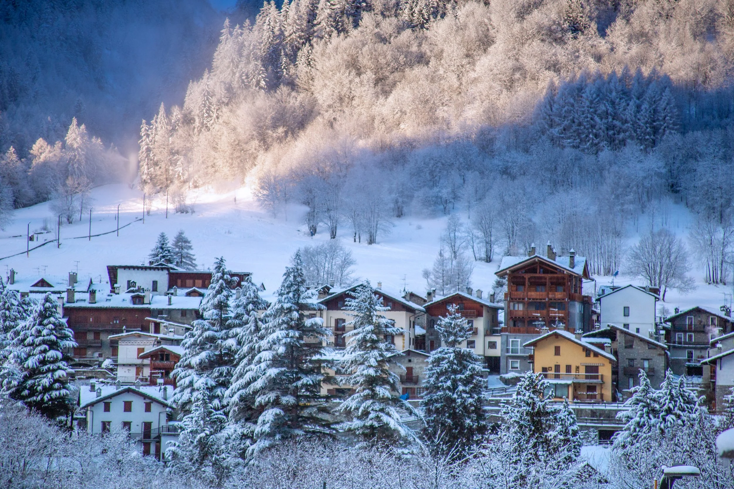A picture of Courmayeur properties in the snow with sunshine on the mountains behind.