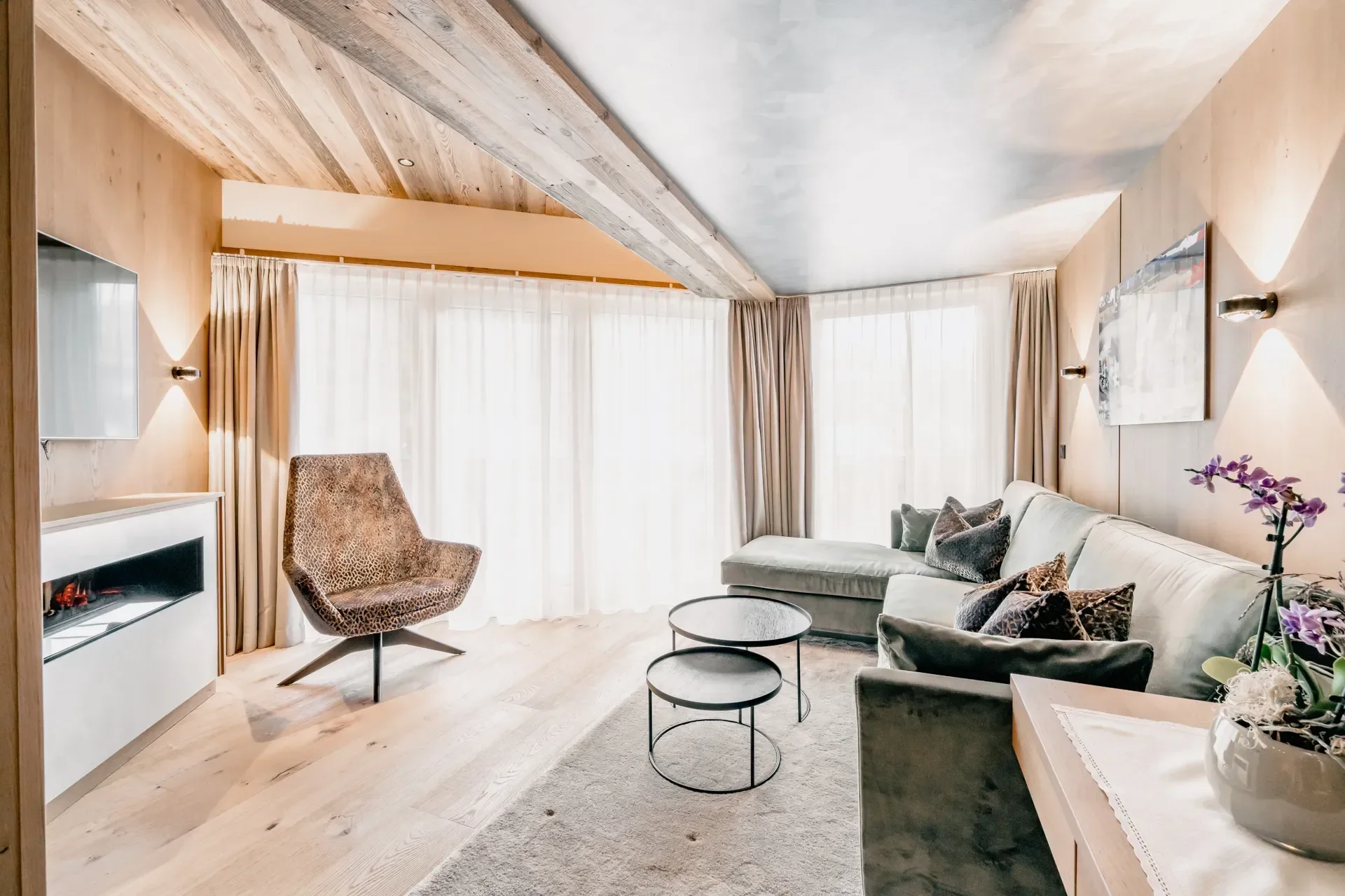 Modern double bedroom with lounge sofa, nesting tables and access to the outside balcony.