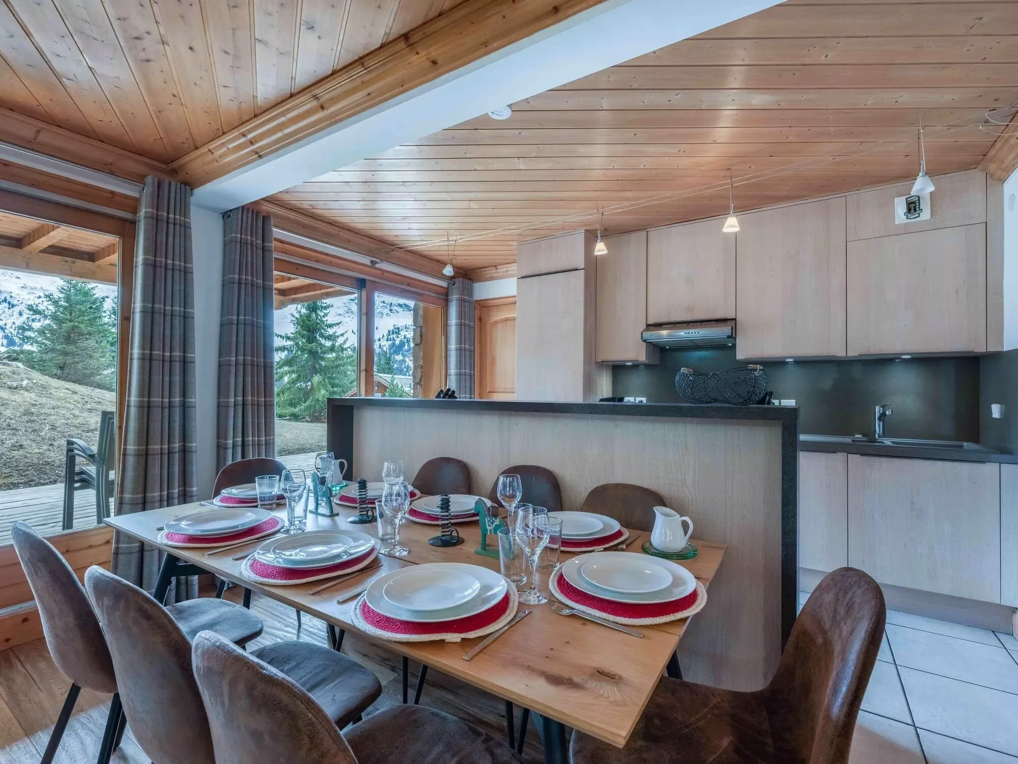 Dining table set for 8. Offering a full laid table, light modern interiors, terrace outside and the kitchen behind. A lovely hosting space.