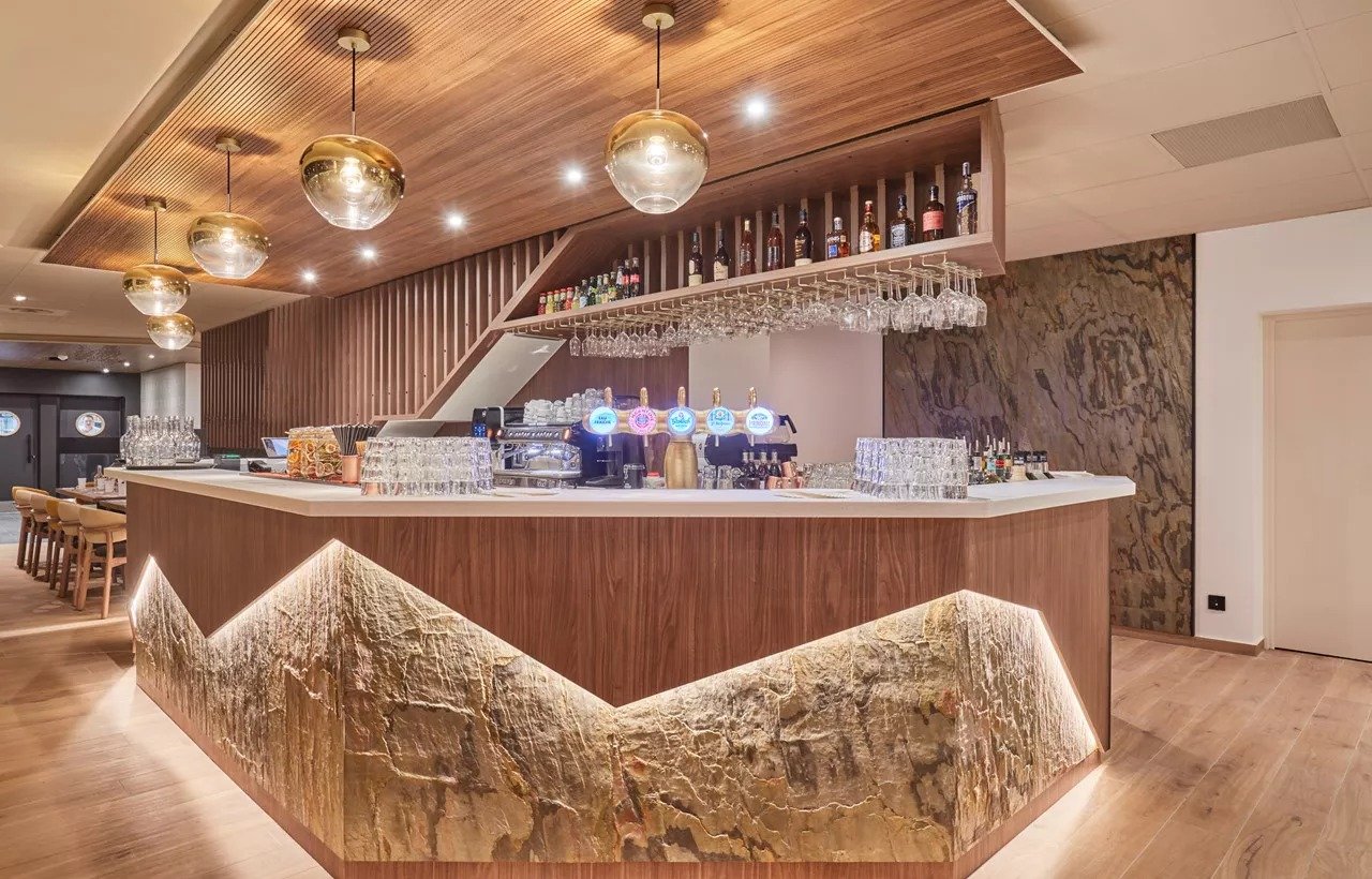 Modern lighting surrounds the bar in the Hotel L'Ecrin blanc. Mountain design cut into the bar.