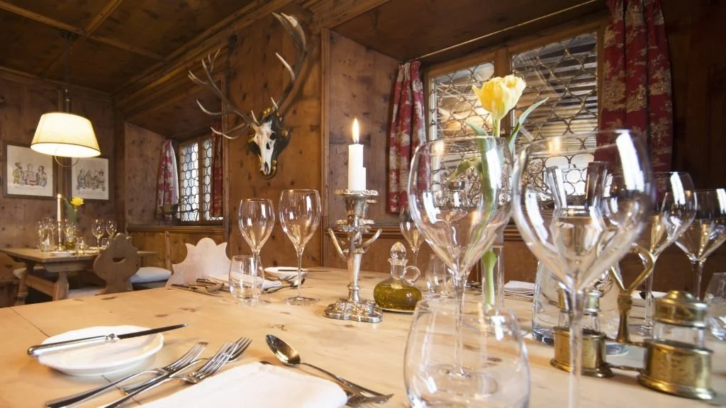 Pine dining table with glassware and antler decoration on the wall.