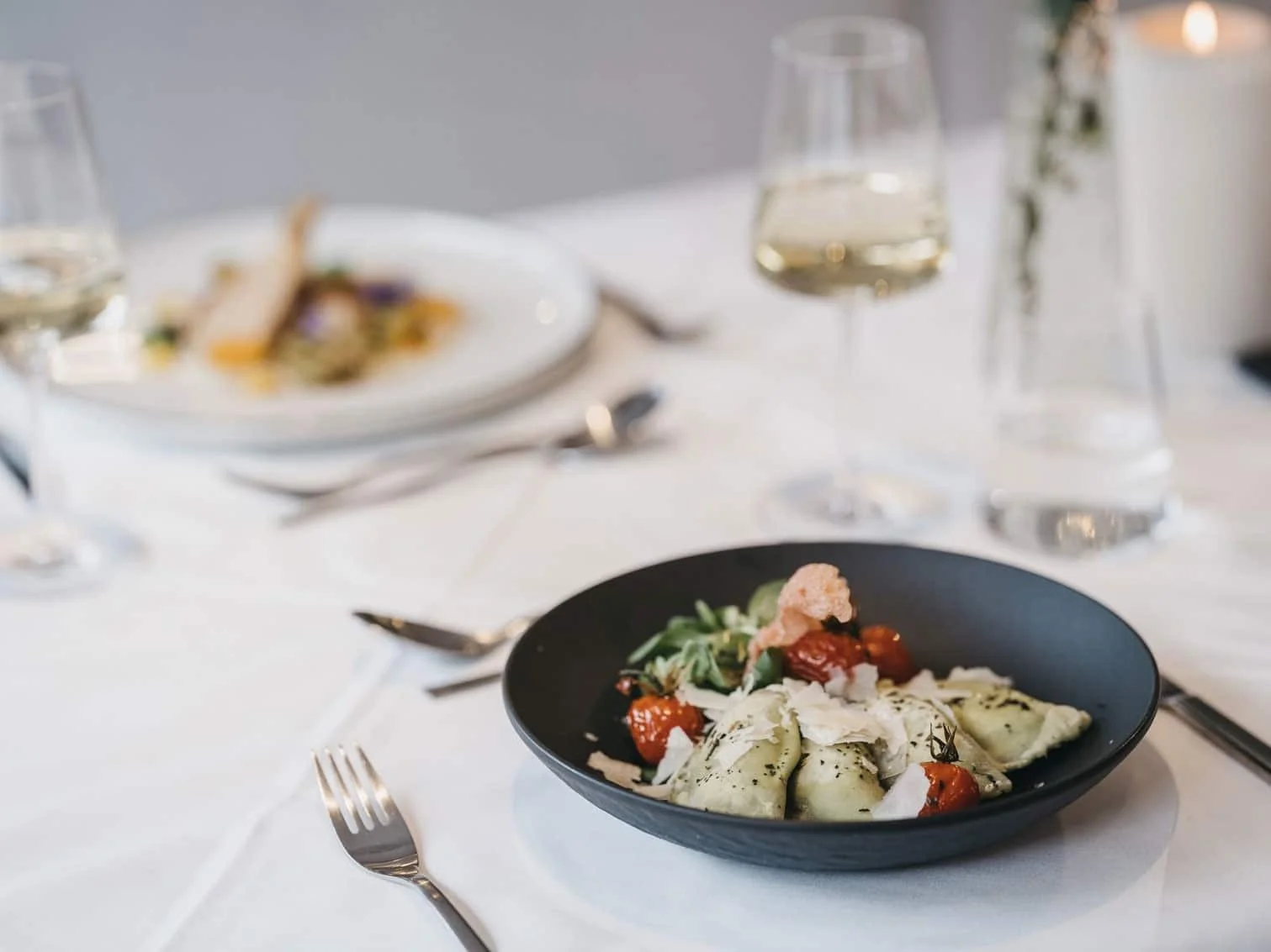 Modern fresh cuisine with pasta, salad and cheese. Set on a white table cloth.