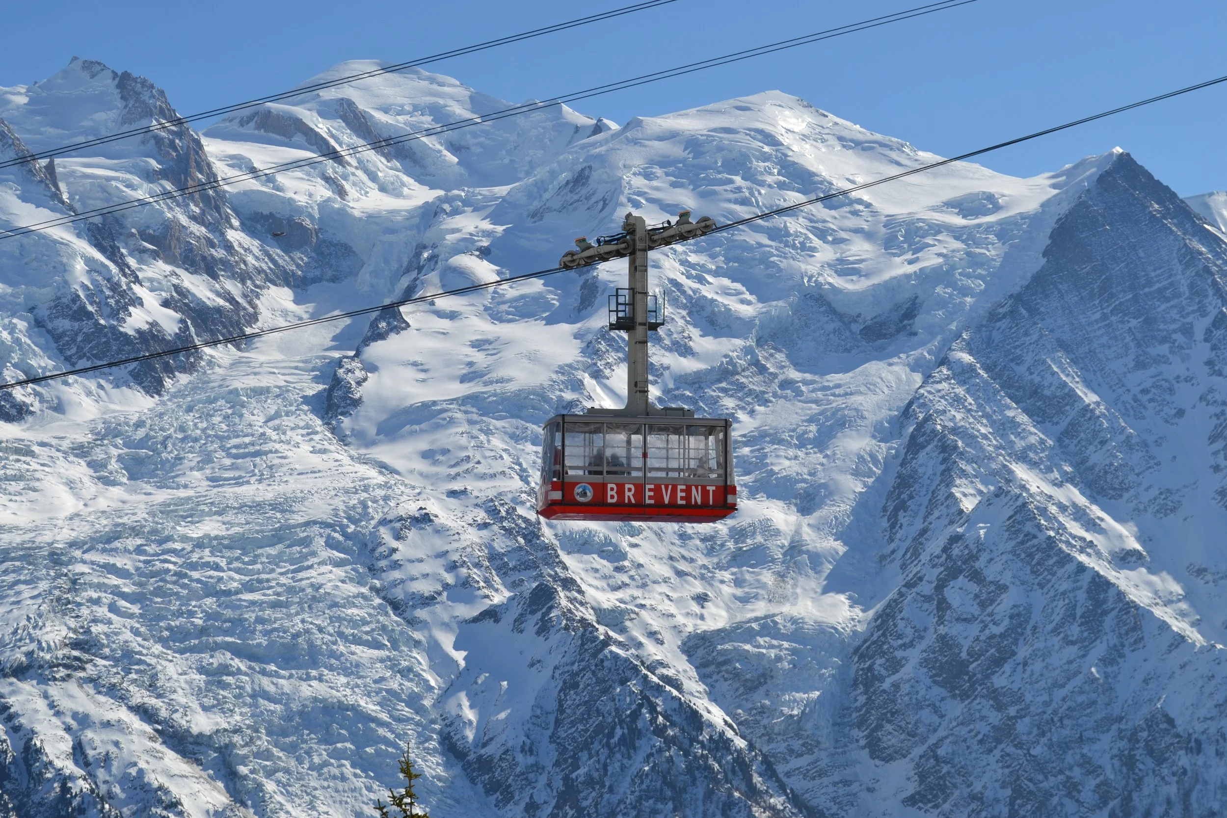 Brevent Gondola going up the mountain Chamonix with the peaks and glacier of Mont Blanc in the background.