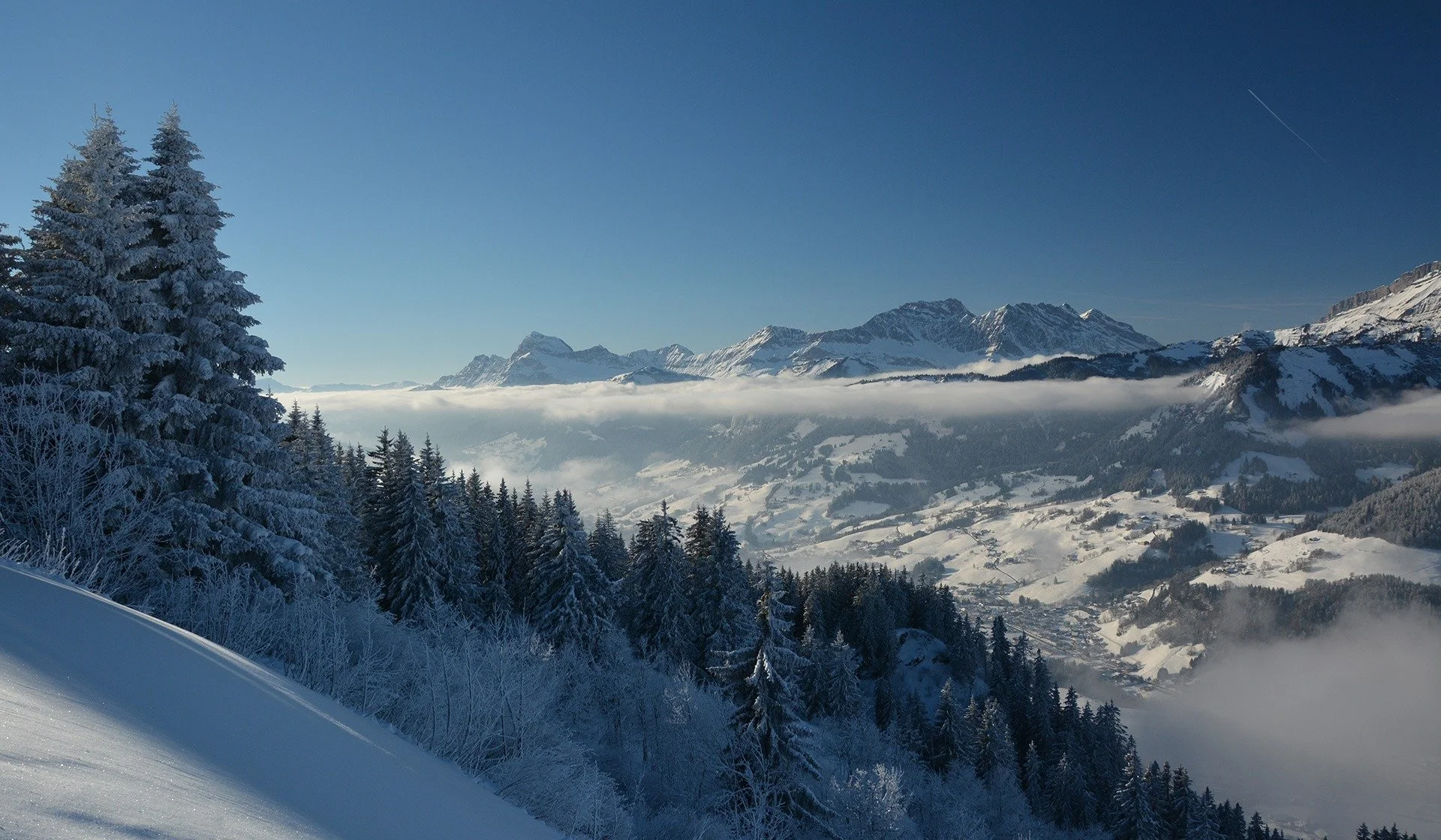 Snowy vista across the mountains in France from Megeve. Fresh snow on the powder pines and tranquil views down the valley.