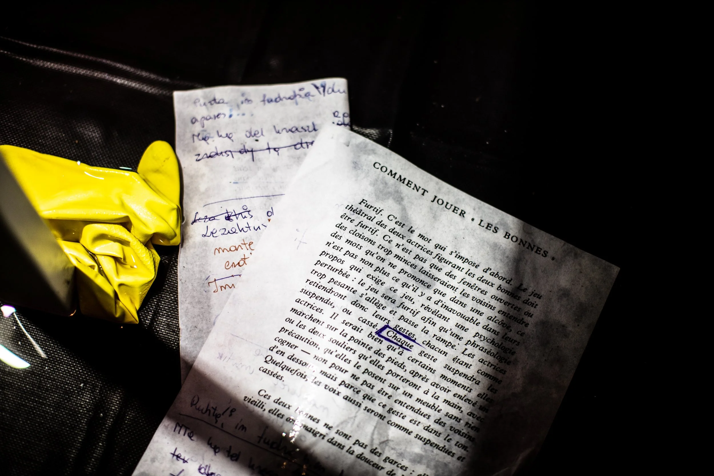 Two sheets of paper, one printed and one handwritten, resting on a black surface, with a yellow plastic bag nearby.