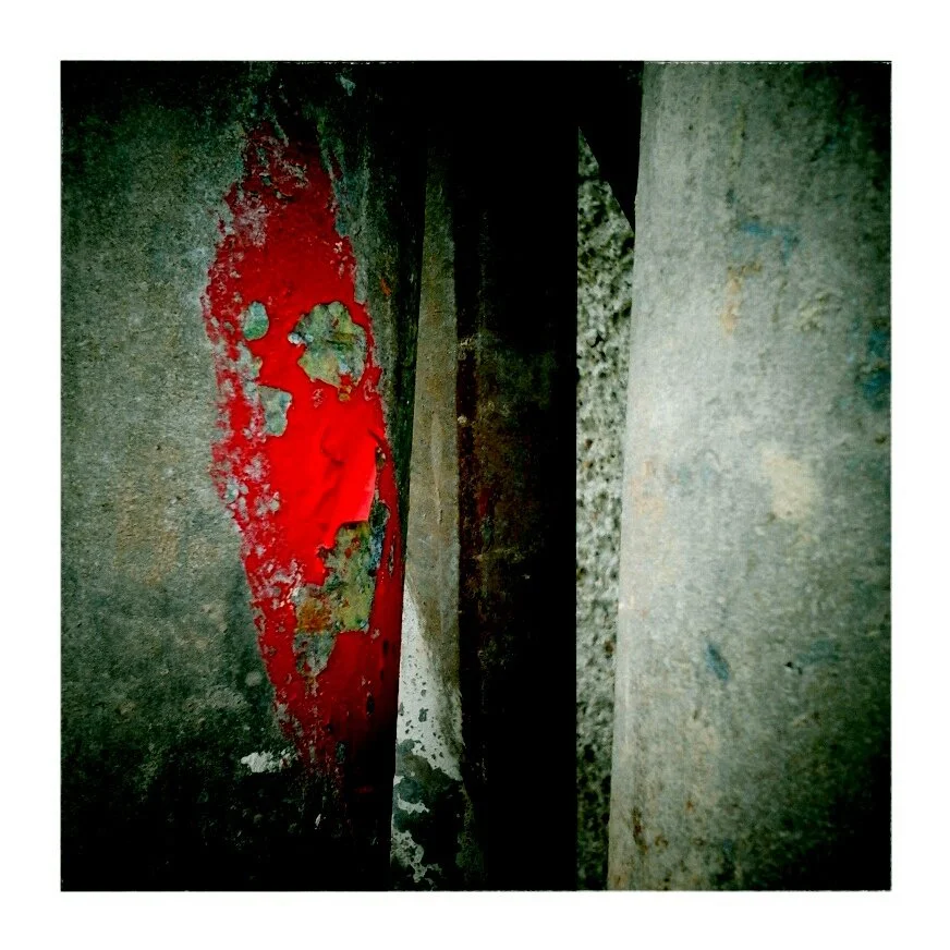 Close-up of a rusted, weathered metal surface with peeling red paint.