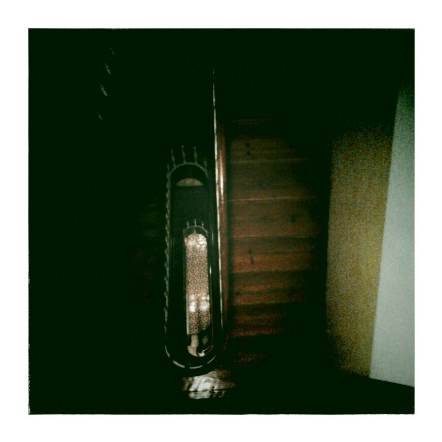 A dark, inclined wooden staircase viewed from above, with a decorative wooden bannister on the left side.