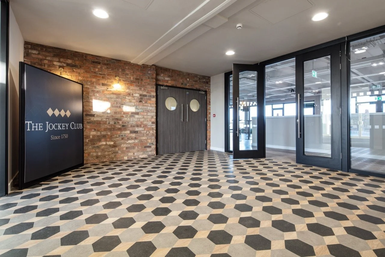 Foyer area with exposed brick and black, grey and cream tiled floor.