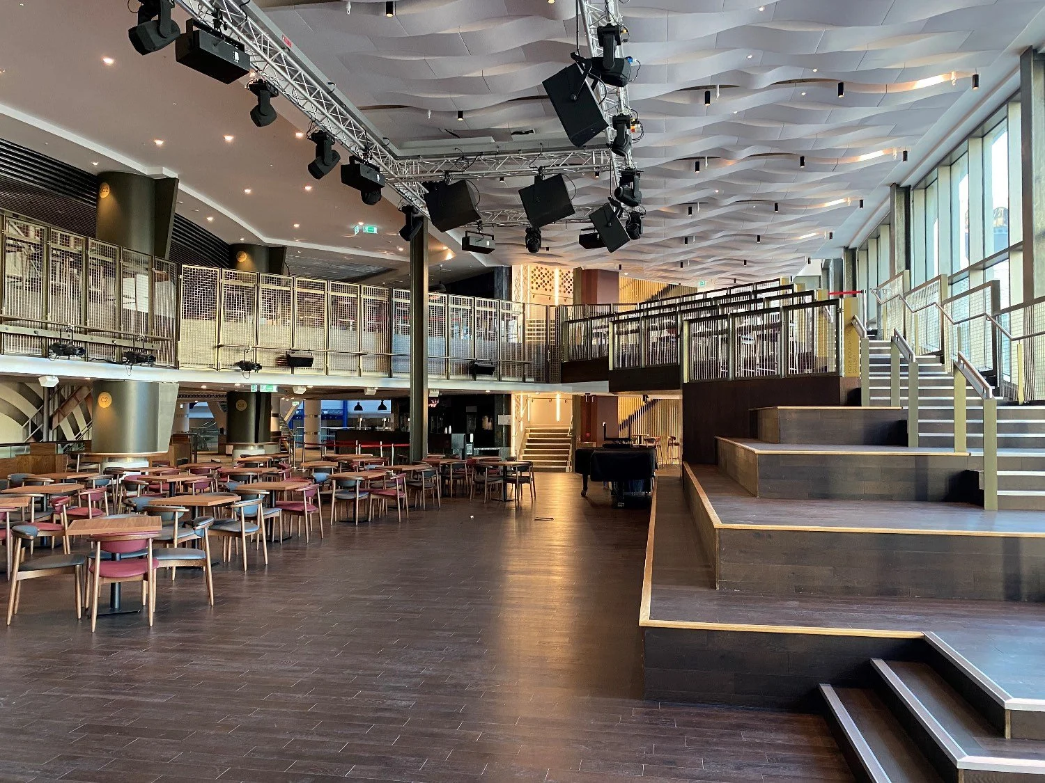 Interior of a leisure area with large stepped performing area, a balcony and chairs and table.