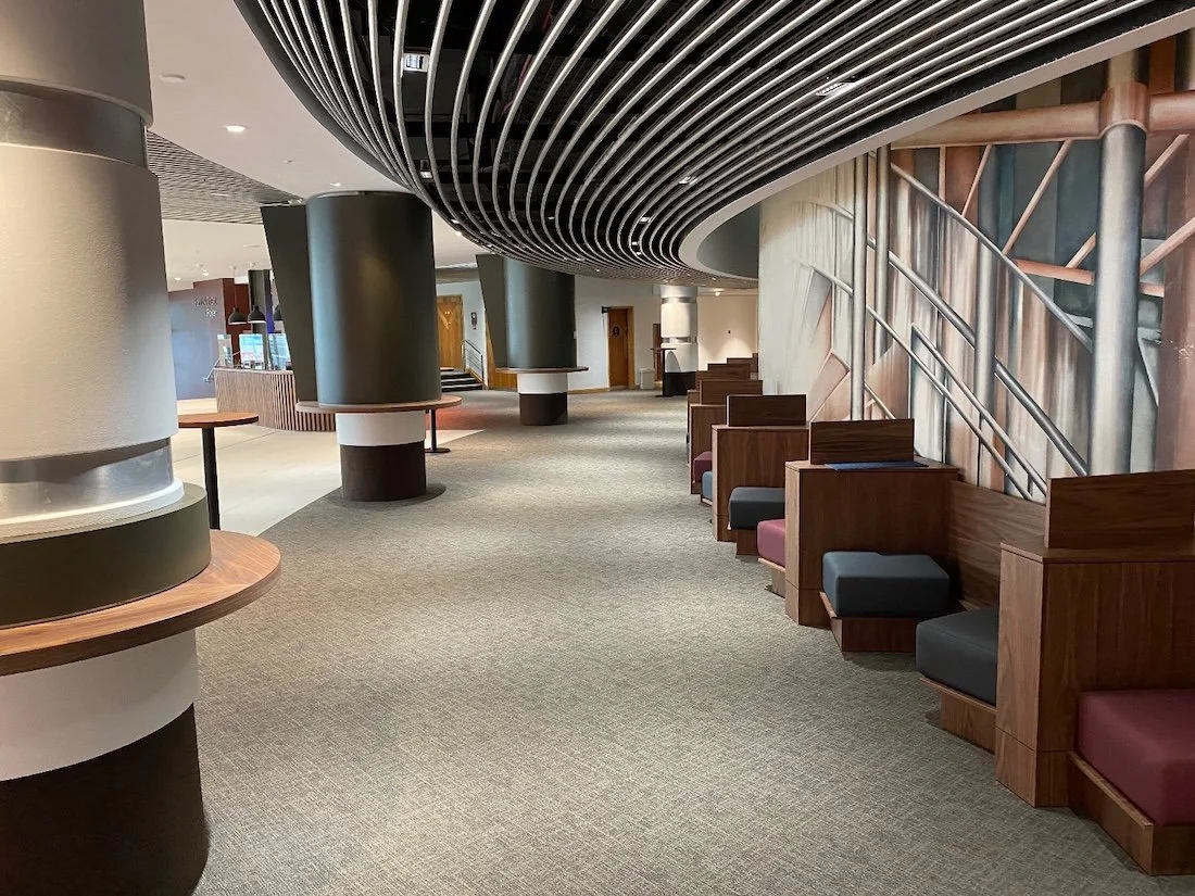Cosy cubicle seating areas with blue, maroon and black cushioned seats in a large social area with white and black columns.