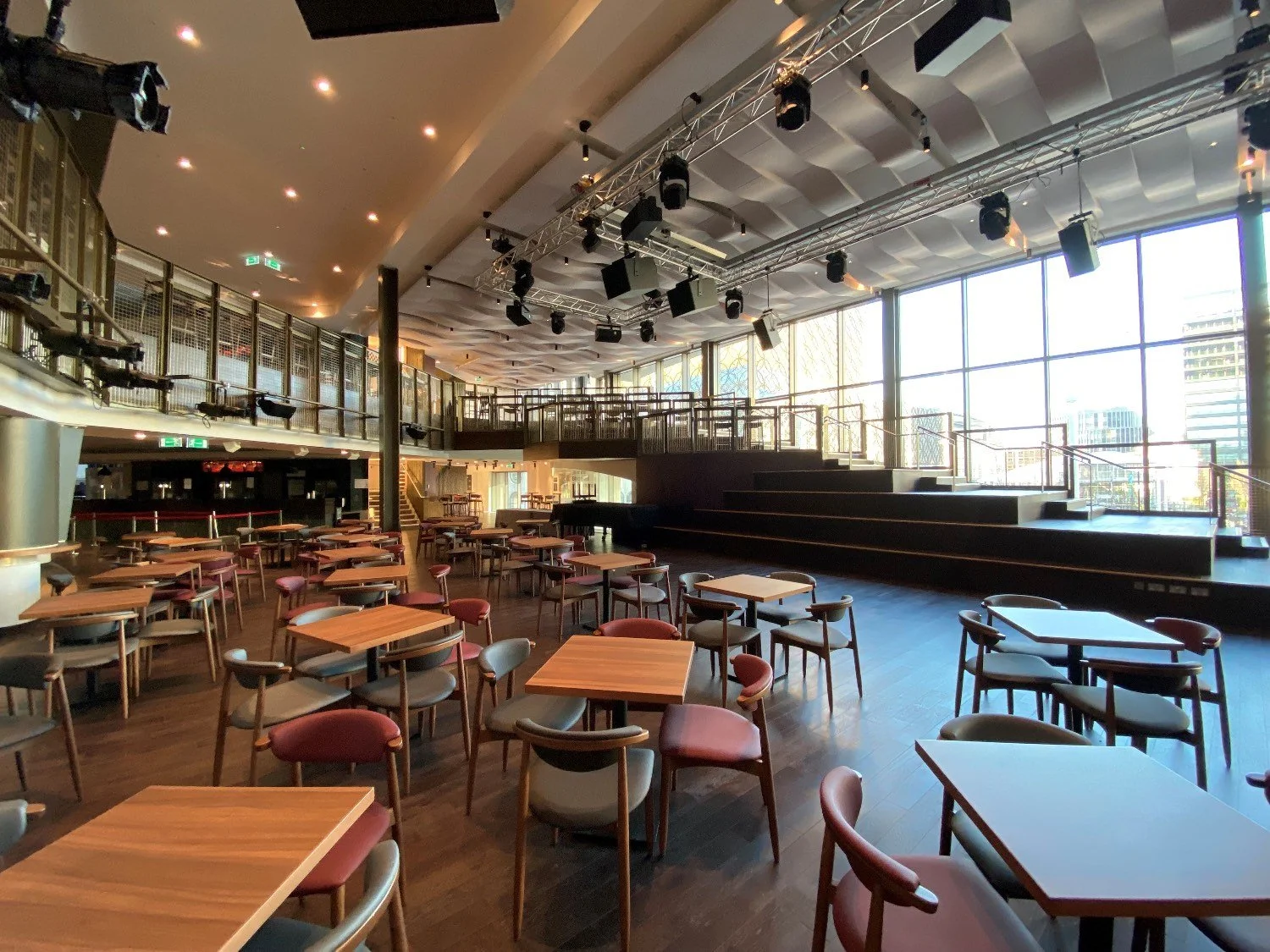 Interior of a leisure area with large stepped performing area, a balcony and chairs and table.