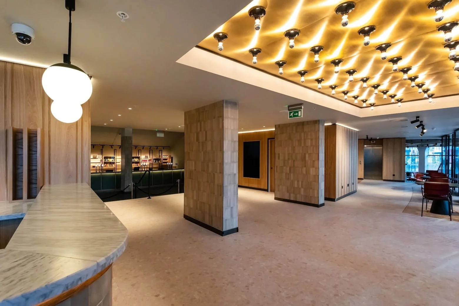 Large, empty leisure venue with thin, long floor-to-ceiling brick pillars and rows of bright golden light bulbs.