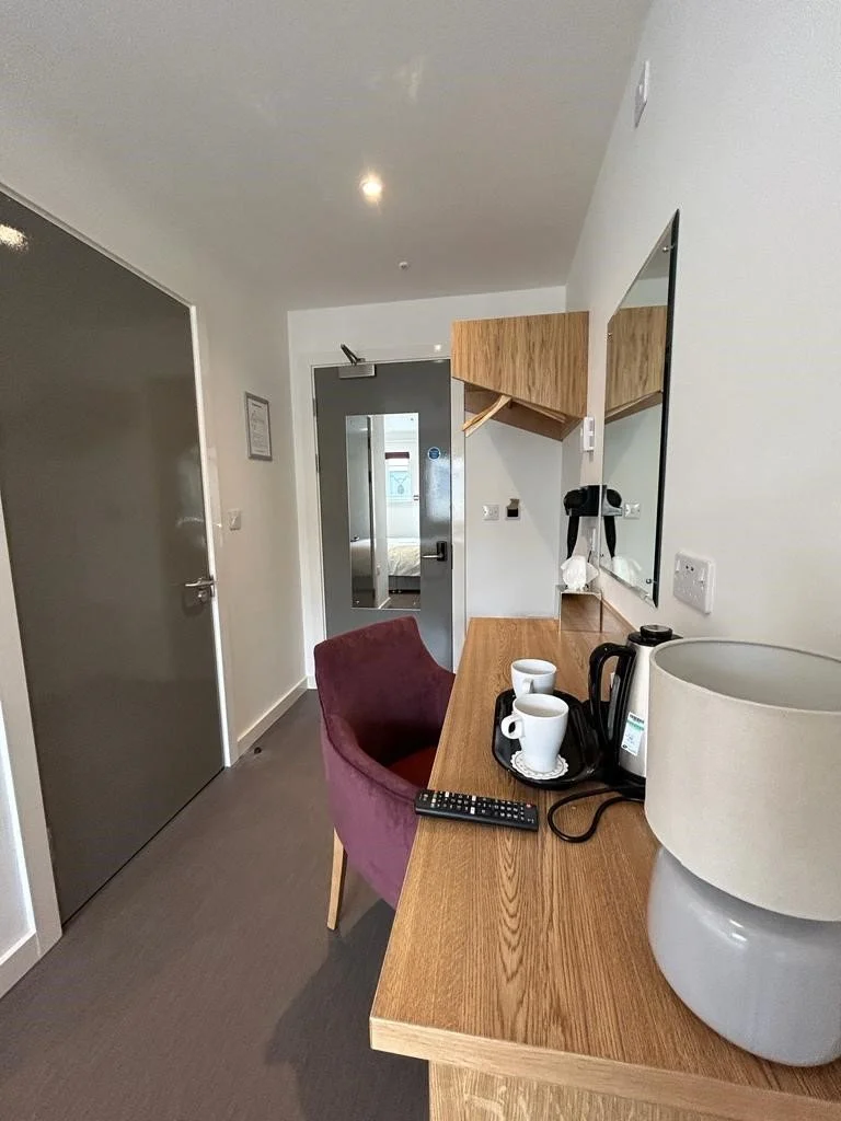 Pine desk in a hotel bedroom with a deep purple desk chair.