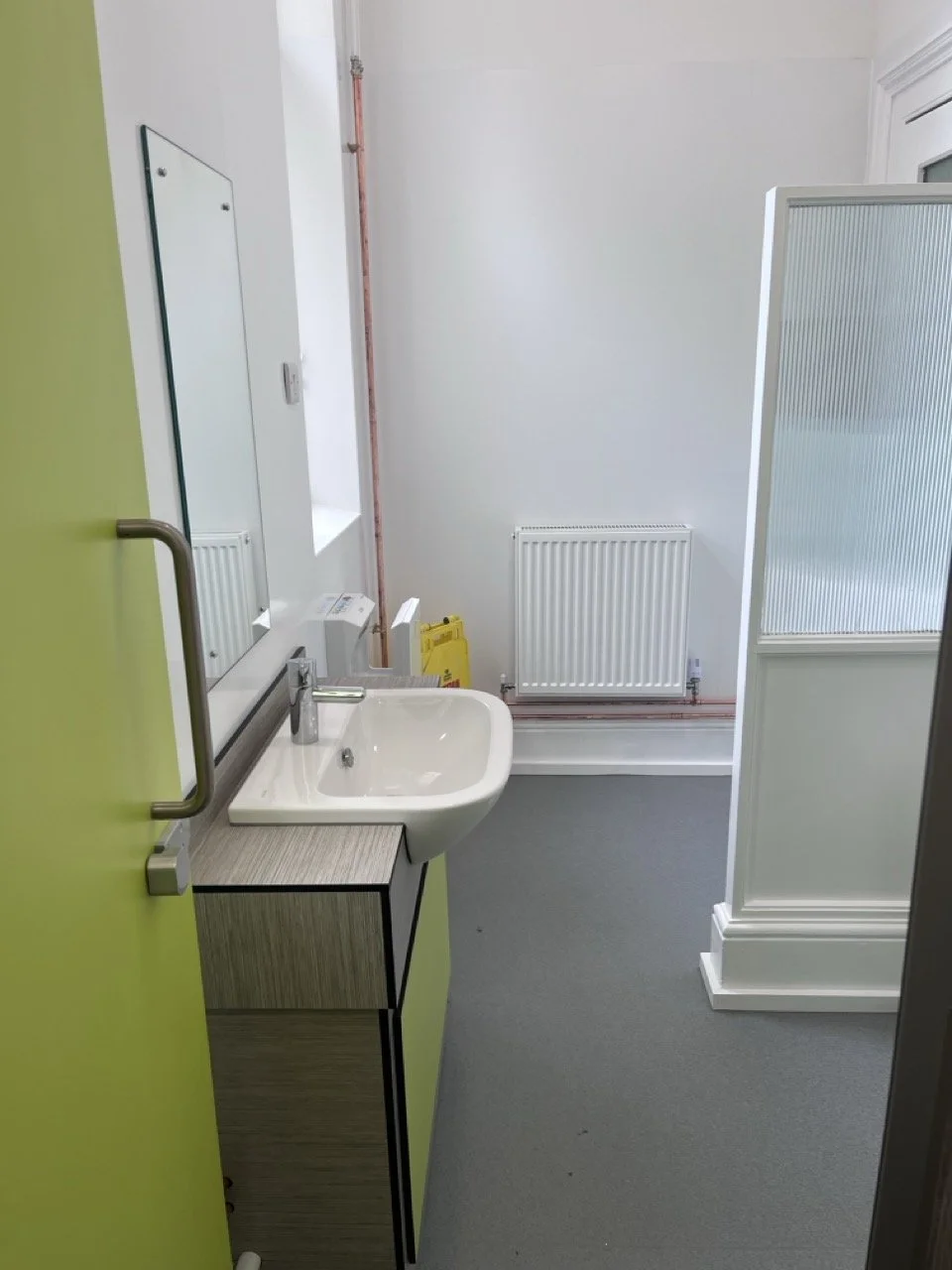 White sink in a toilet area with a lime green door.