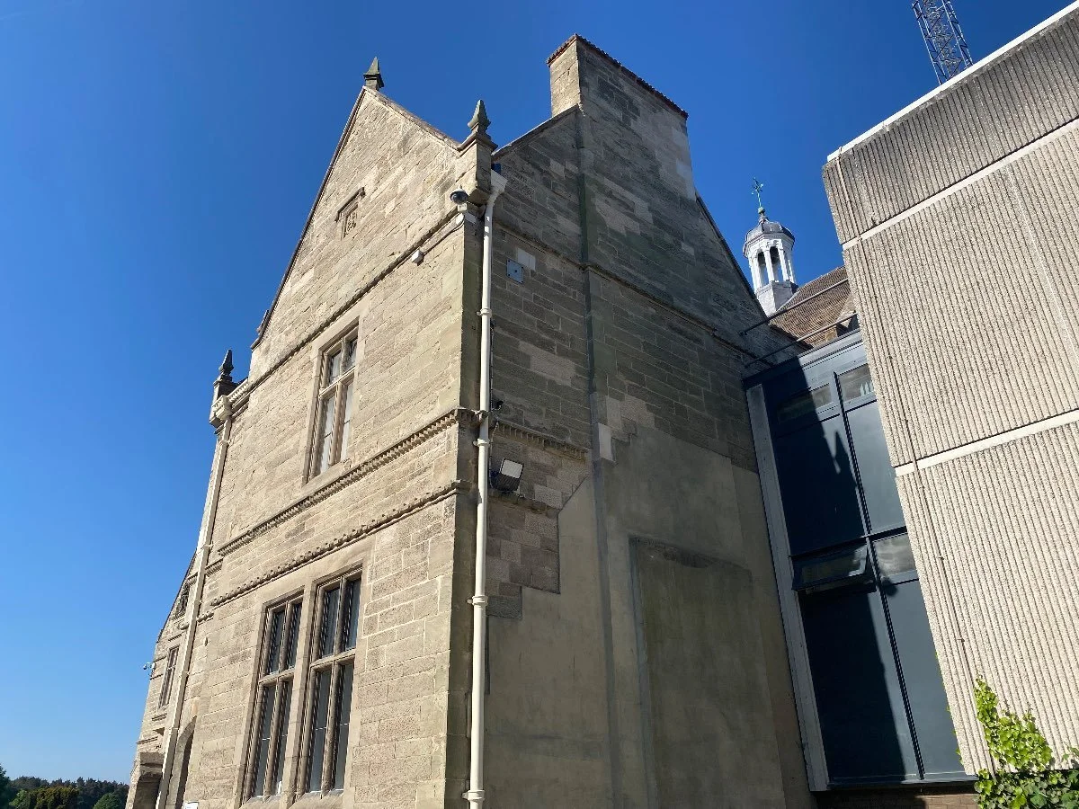 Looking up at a large stone building on a sunny day with blue skies.