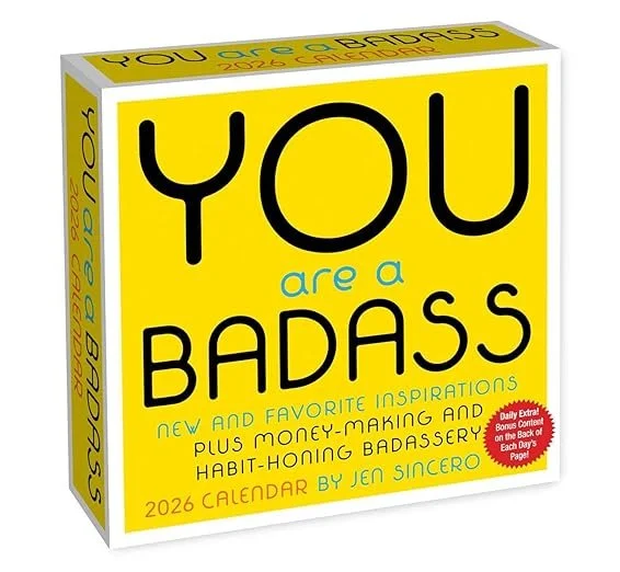 A 2026 calendar titled "You are a Badass" by Jen Sincero, with a bright yellow cover featuring bold black and turquoise text and a red sticker indicating a daily extra bonus content.