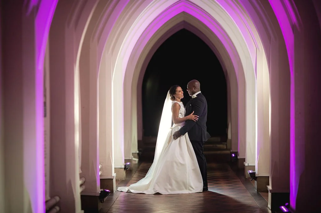 A bride and groom dancing in a decorated archway at their wedding reception.