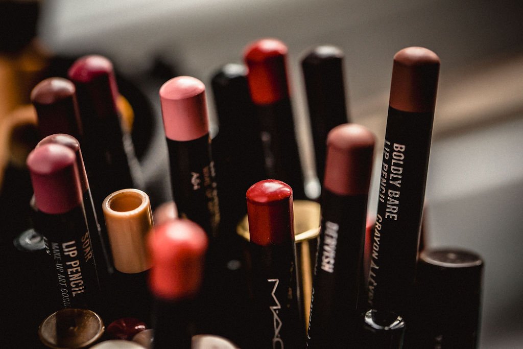 Close-up of various lipsticks in different shades and packaging standing upright.