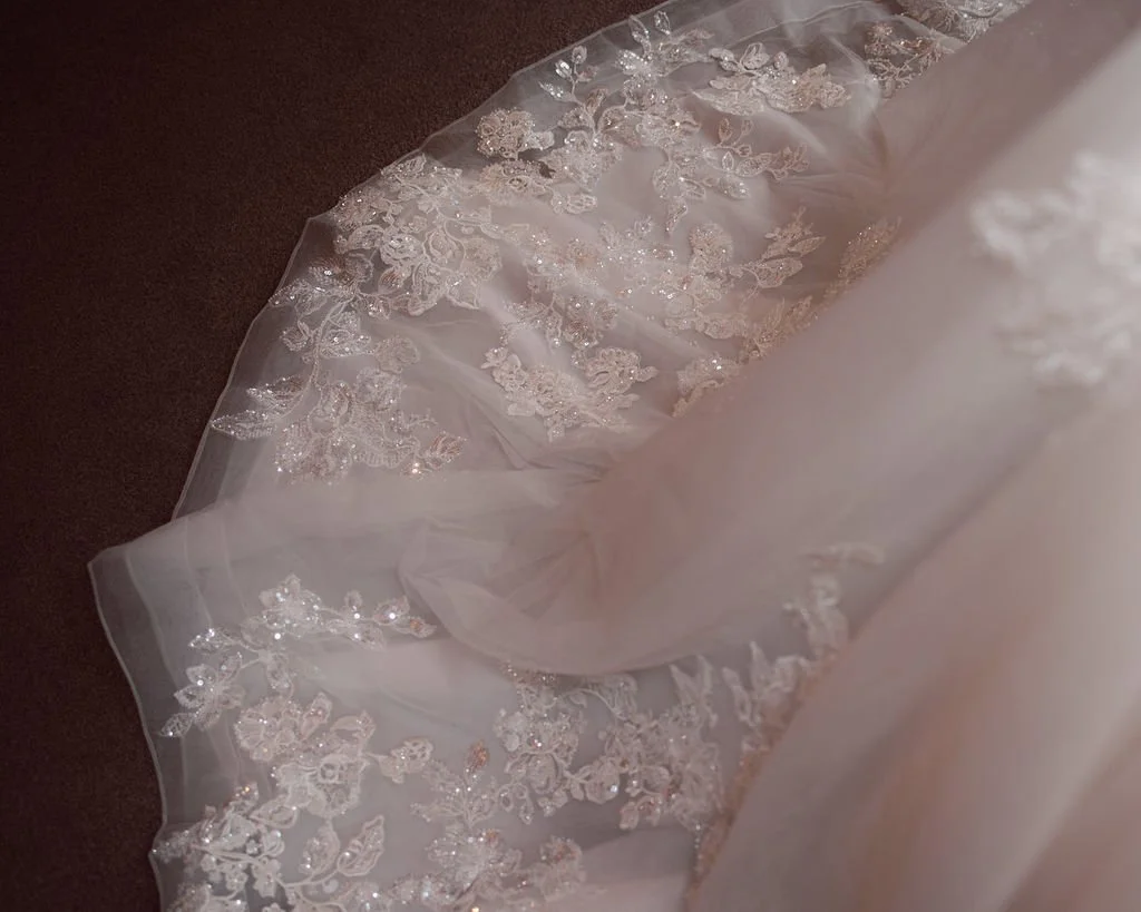 Close-up of a white wedding dress with intricate lace and beadwork.