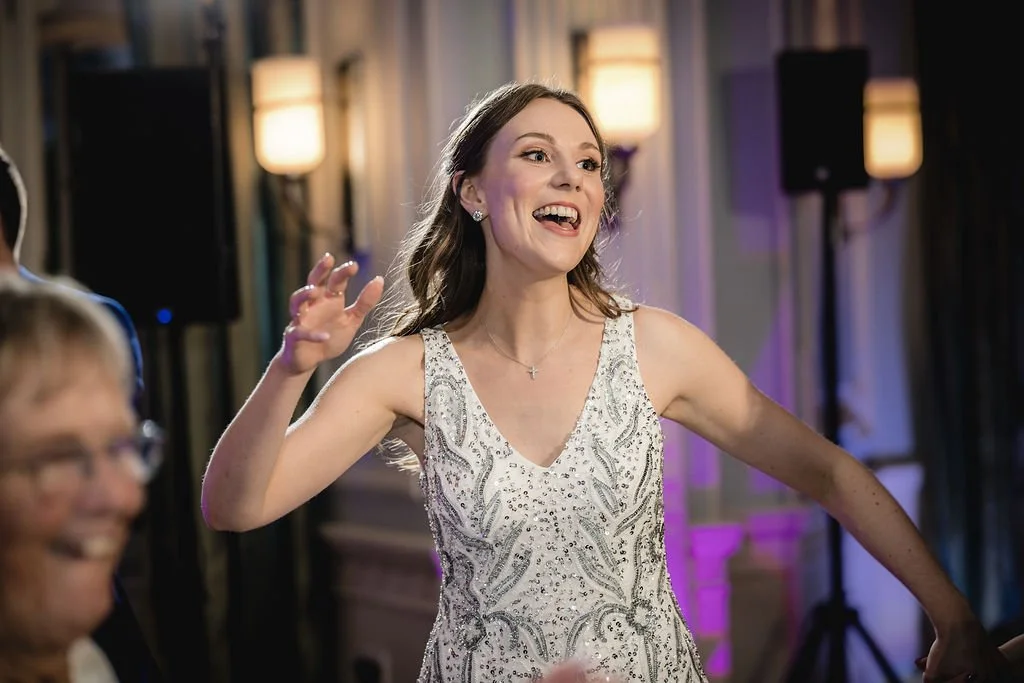 A woman in an elegant dress smiling and dancing at a celebration or party.