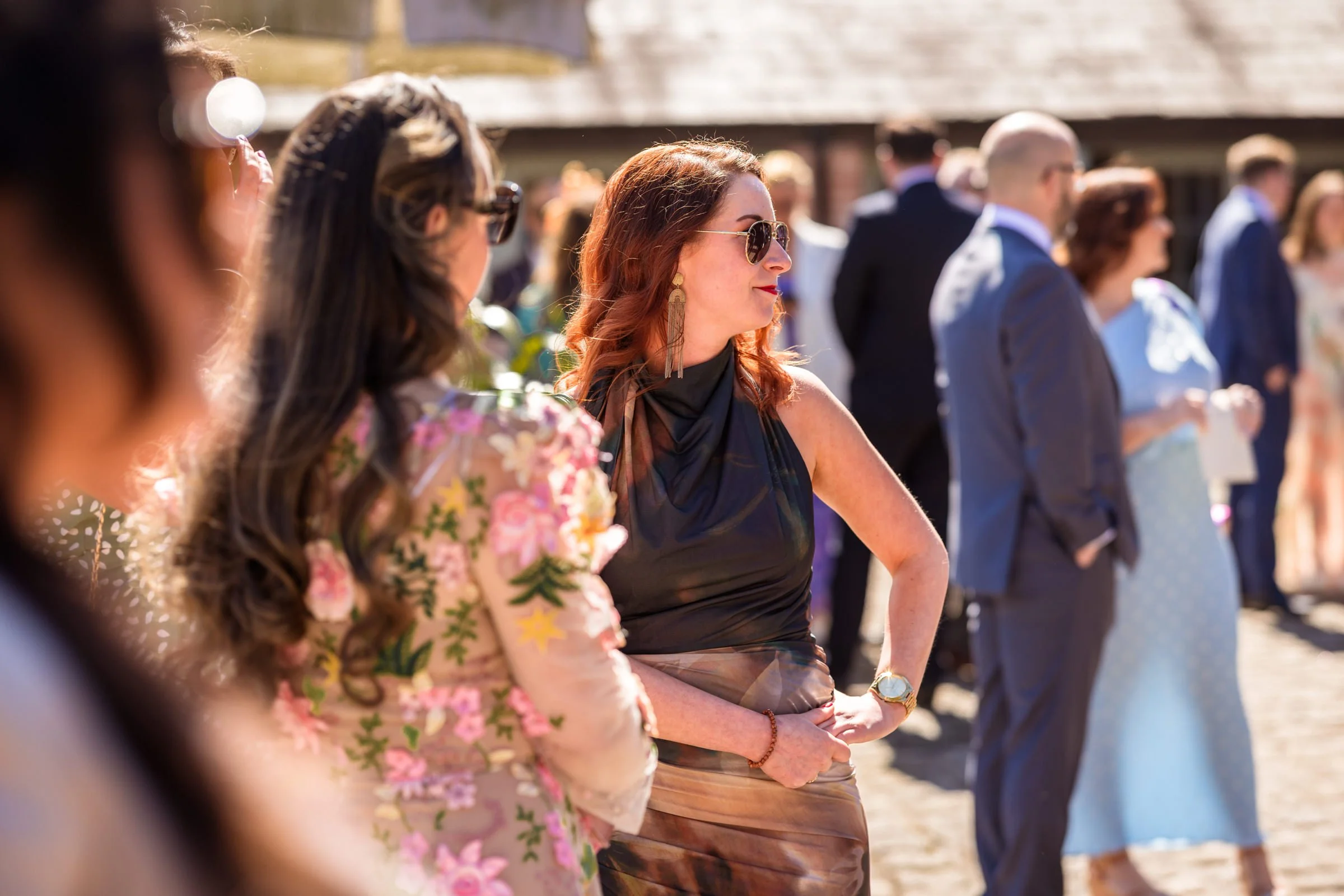 People dressed in formal attire at an outdoor event, standing in a line.