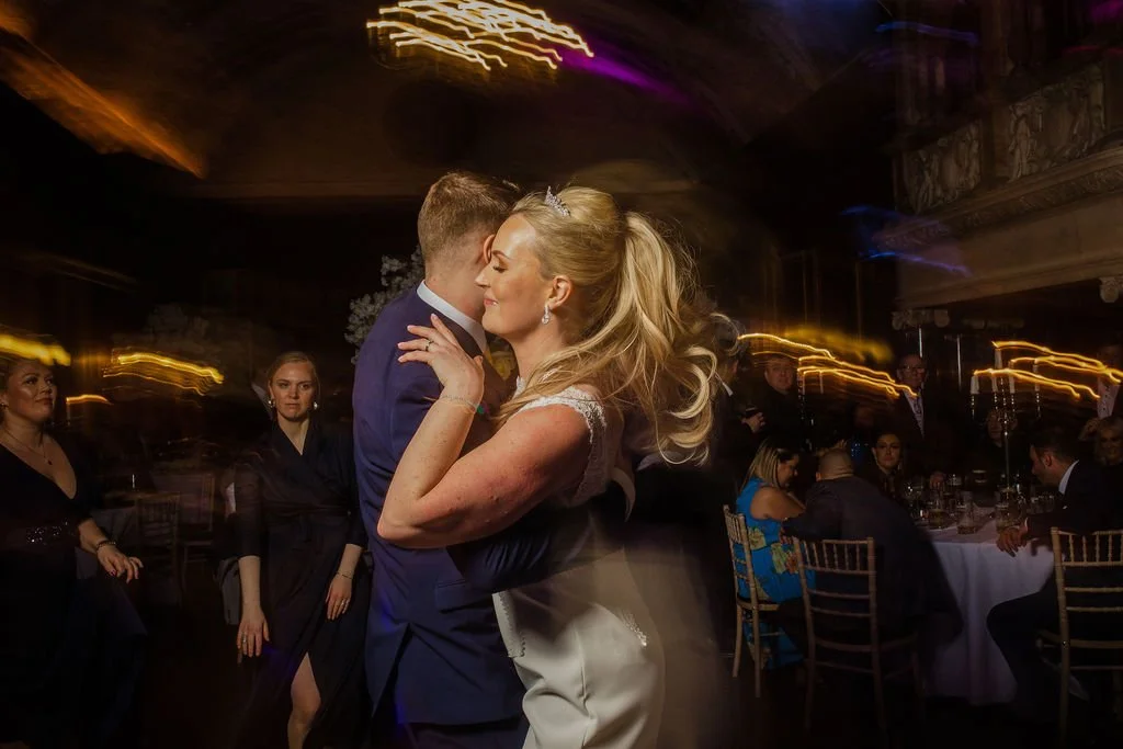 Bride and groom sharing a dance at their wedding reception with guests watching.