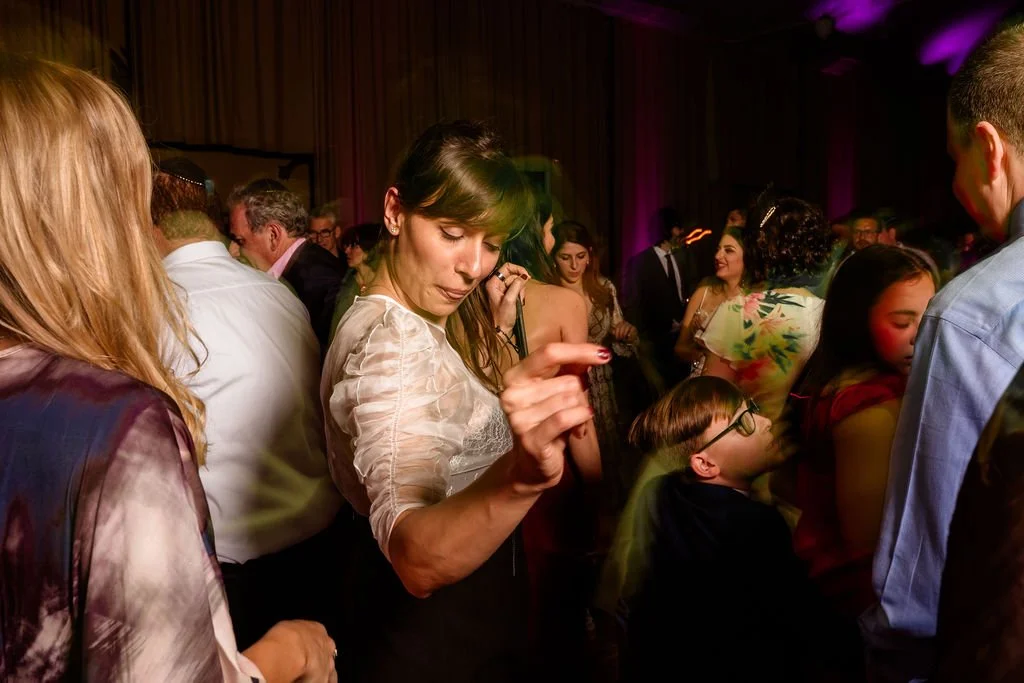 People dancing and socializing at a crowded indoor event with colorful lighting.