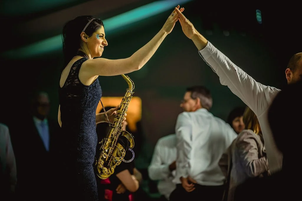 A woman with a saxophone high-fives a man at a social event or party.