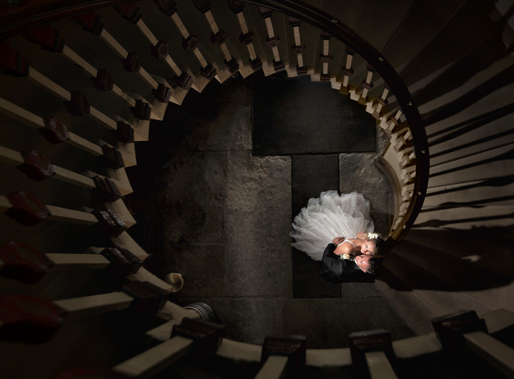Brdie and groom embrace each other at the centre of a spiralling staircase