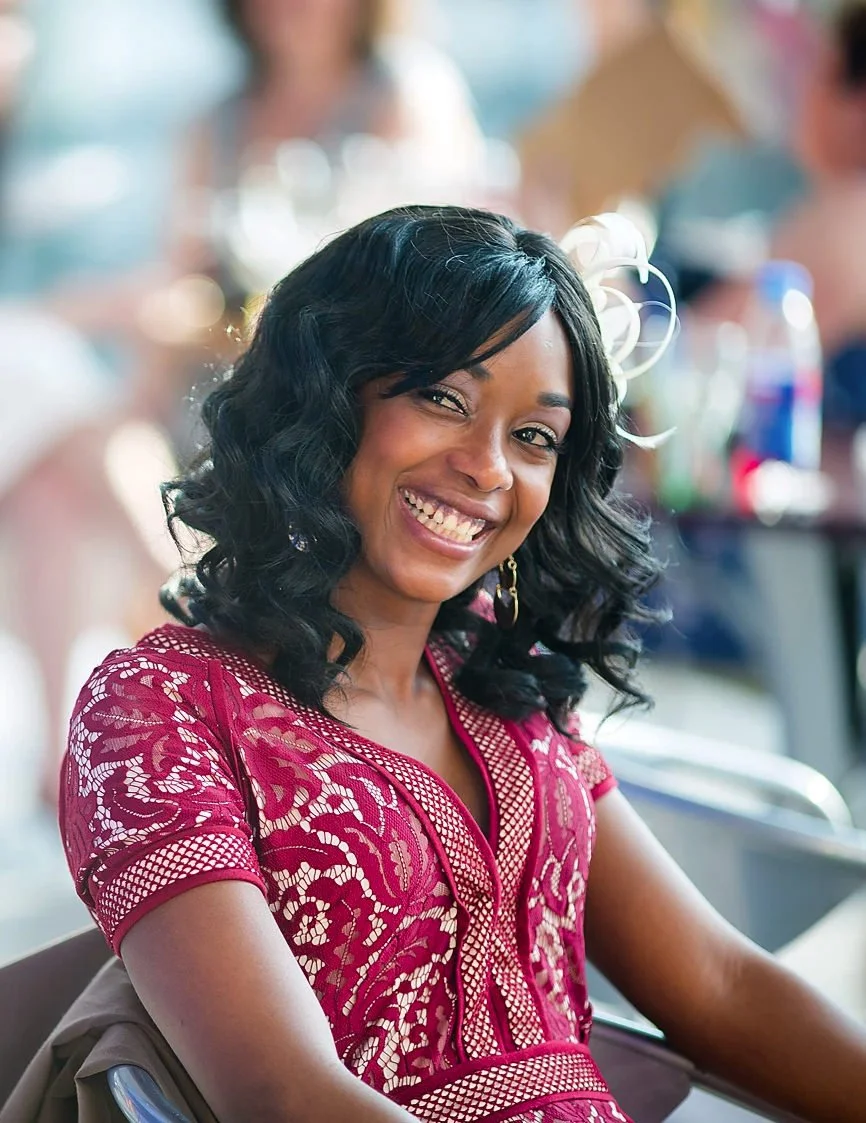 Beautiful smiling young female wedding guest wearing decorative red dress sat at table