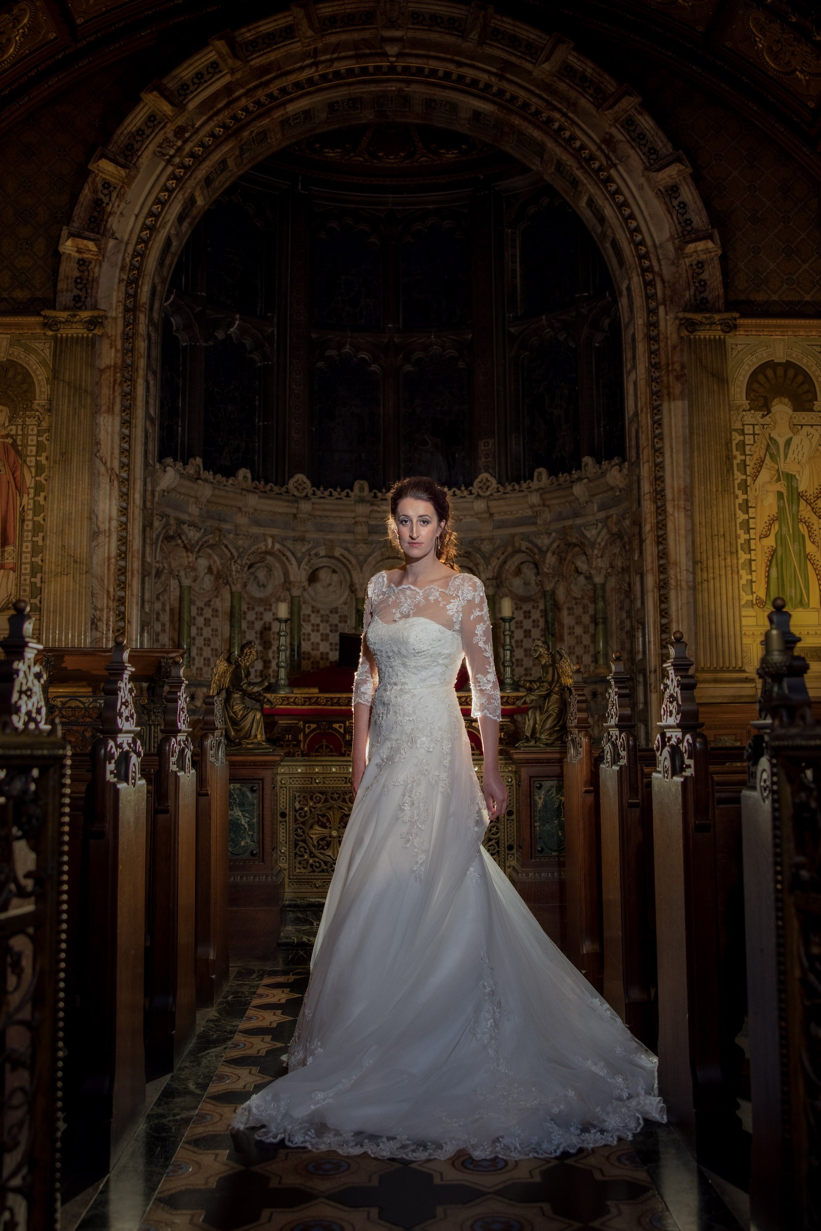A woman in a wedding dress standing inside a historic church or cathedral with ornate architecture and religious artwork.
