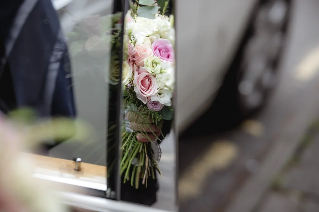A bouquet of pink and white roses reflected in a mirror.