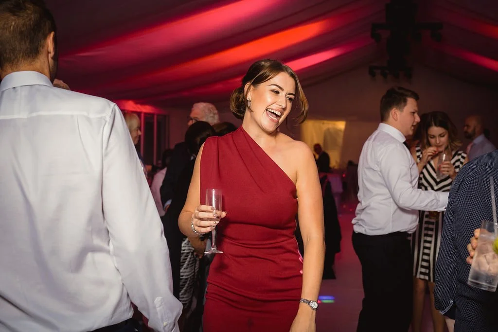 Woman in a red dress smiling and holding a glass at a party or social event