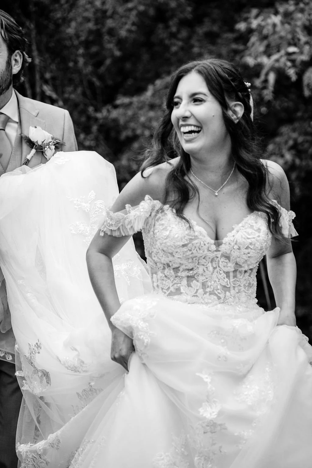 A woman in a wedding dress smiling while holding up her dress during a wedding celebration.