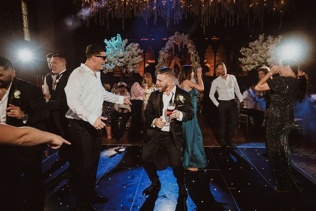 People dancing and celebrating at a formal event or wedding reception on a decorated dance floor.