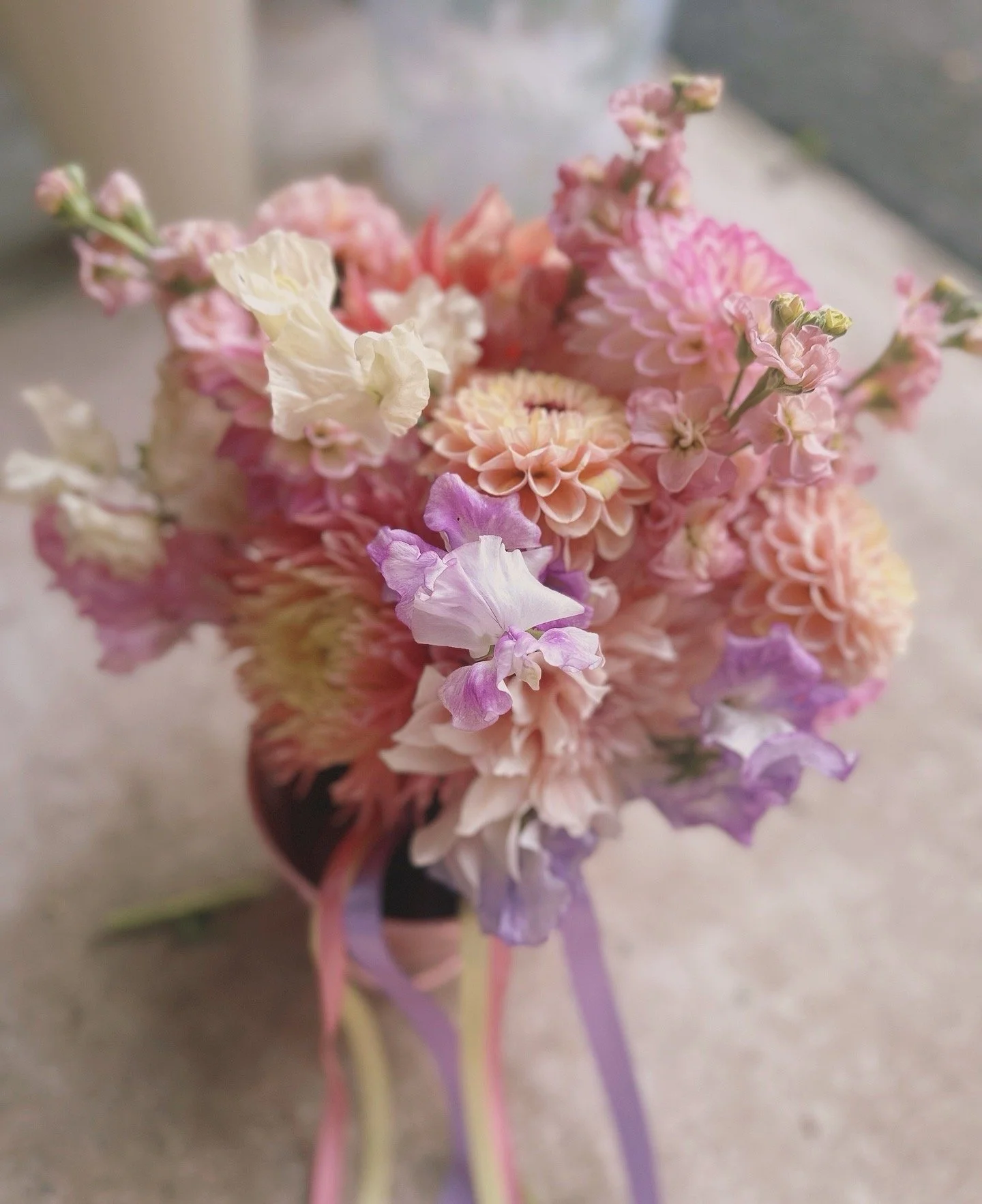 A bouquet of pink, white, and purple flowers in a vase with purple ribbons.