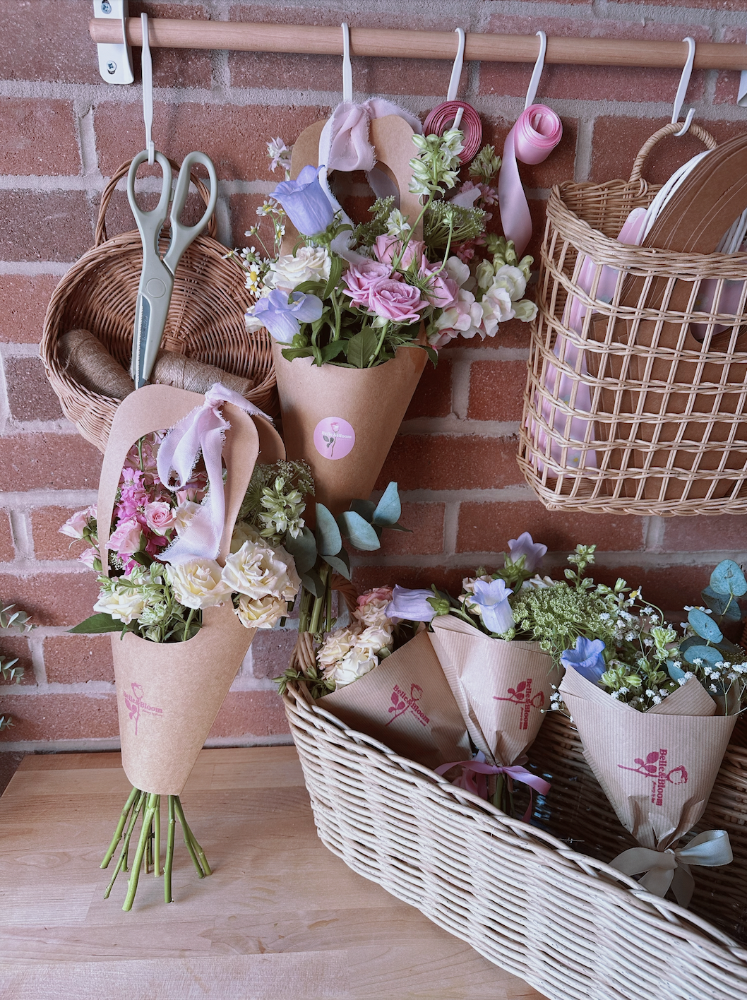 Arrangement of flower bouquets and gardening tools against a brick wall, including scissors and ribbon.