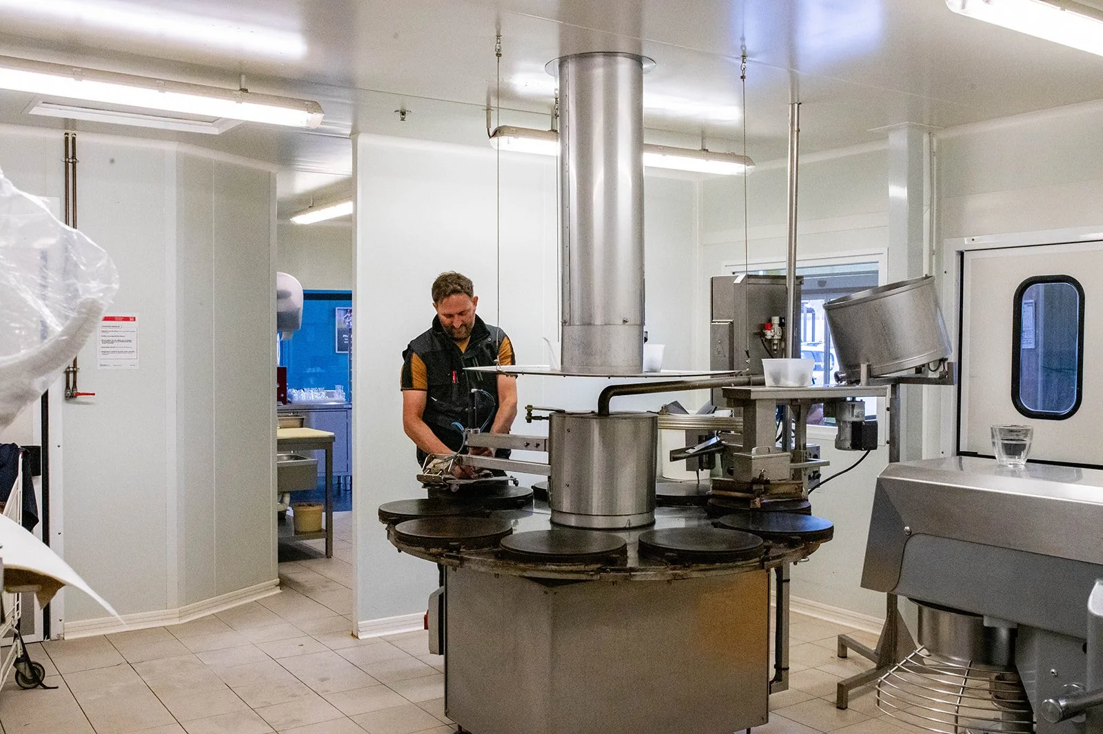 Un homme travaille dans une crêperie bretonne, entouré d'équipements en acier inoxydable.