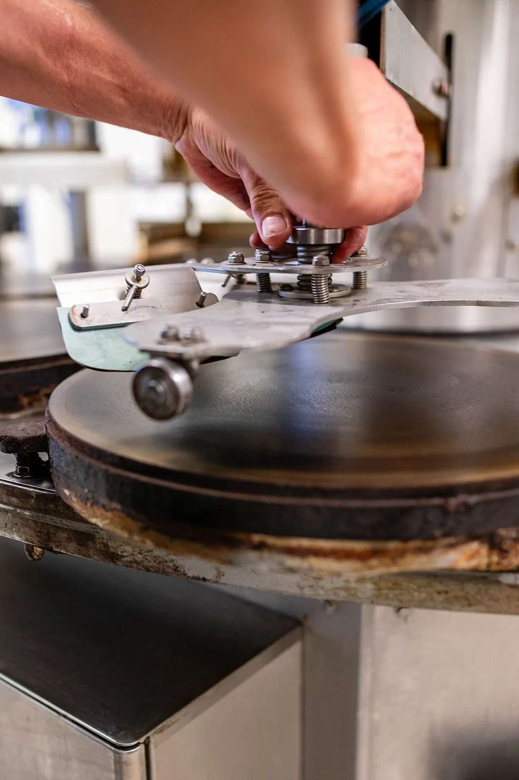 A hand adjusting a rotating disc on an industrial turntable, probably used for manufacturing or processing materials.