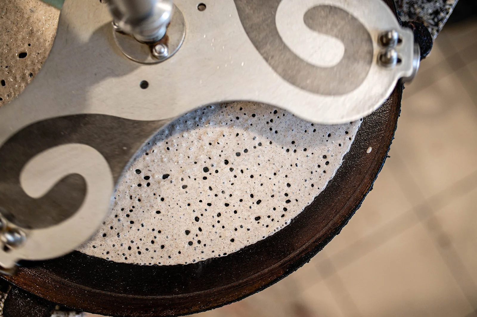 Une surface de fer à estamer avec une fine couche de pâte à crêpes prête à cuire, vue en gros plan.