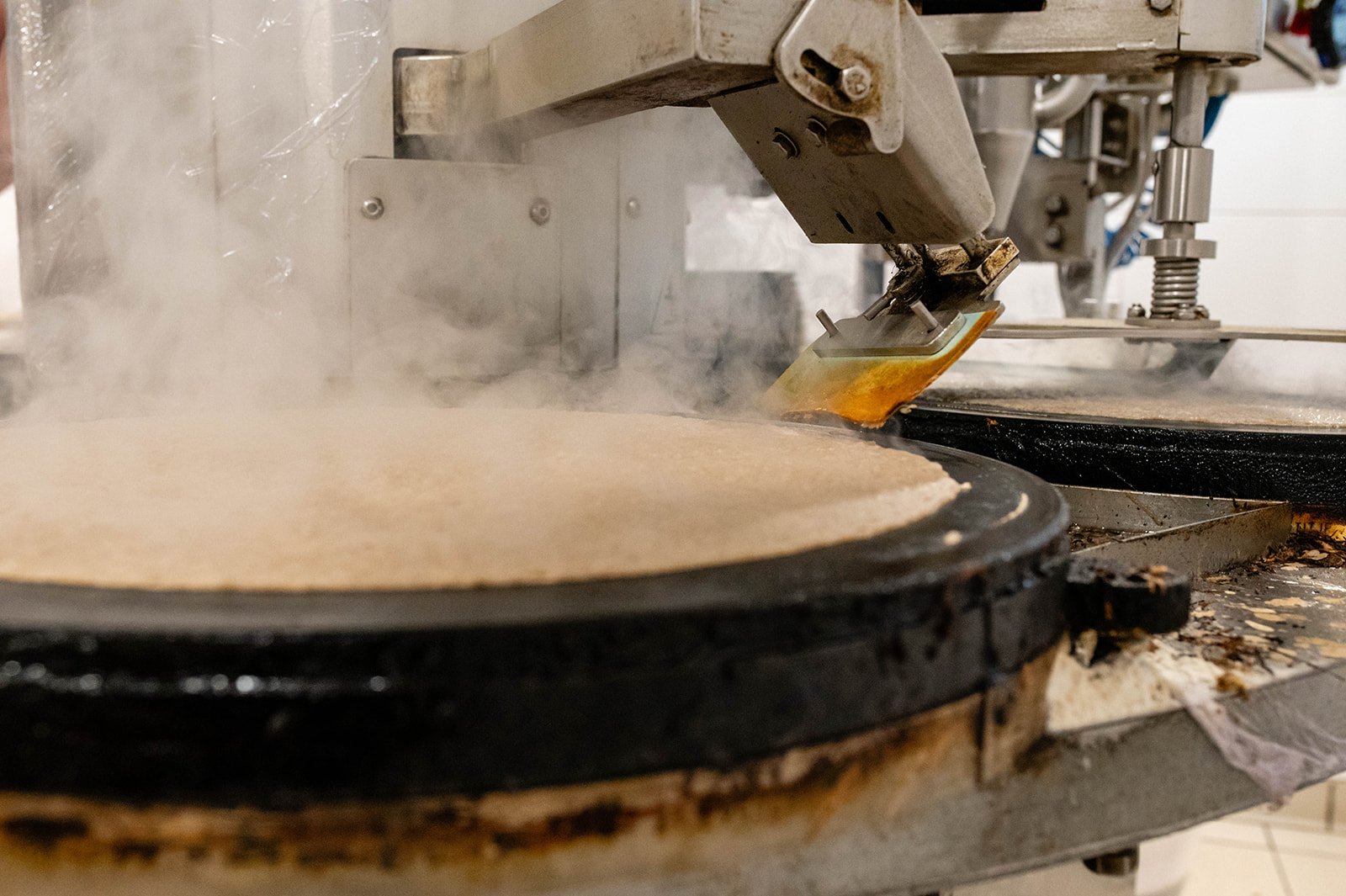 Machine used to make pancakes or galettes, with steam escaping.