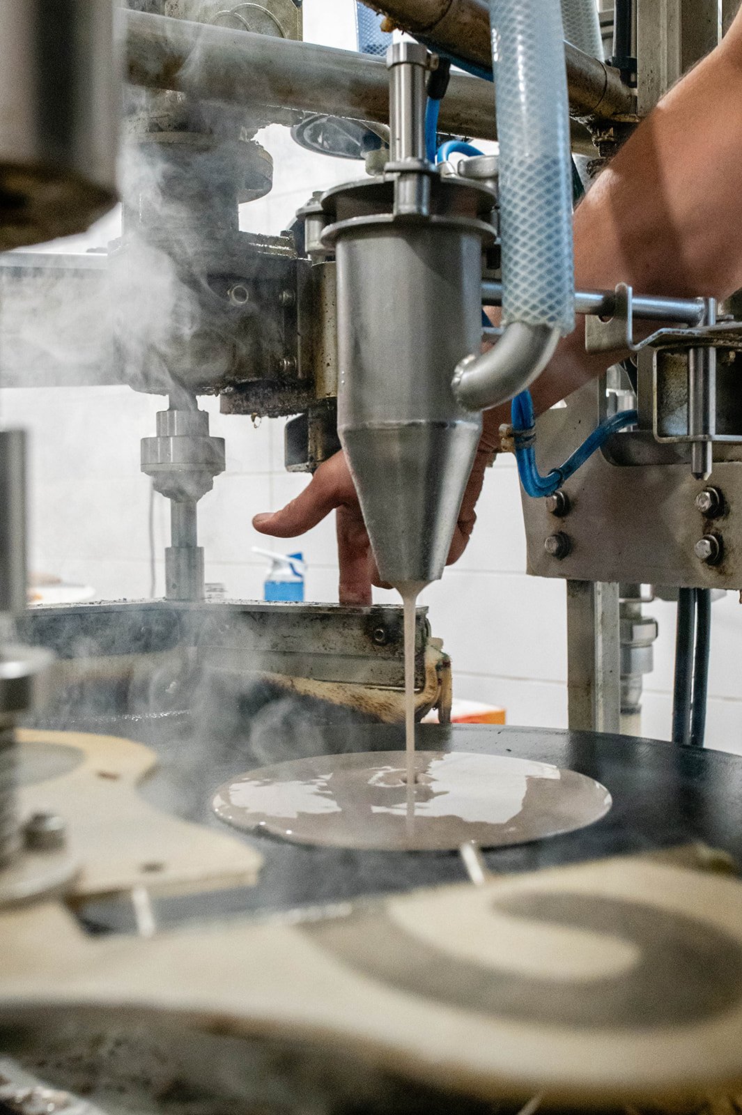 Liquid intake on a small-scale production machine, with operator's hand, in a manufacturing environment.