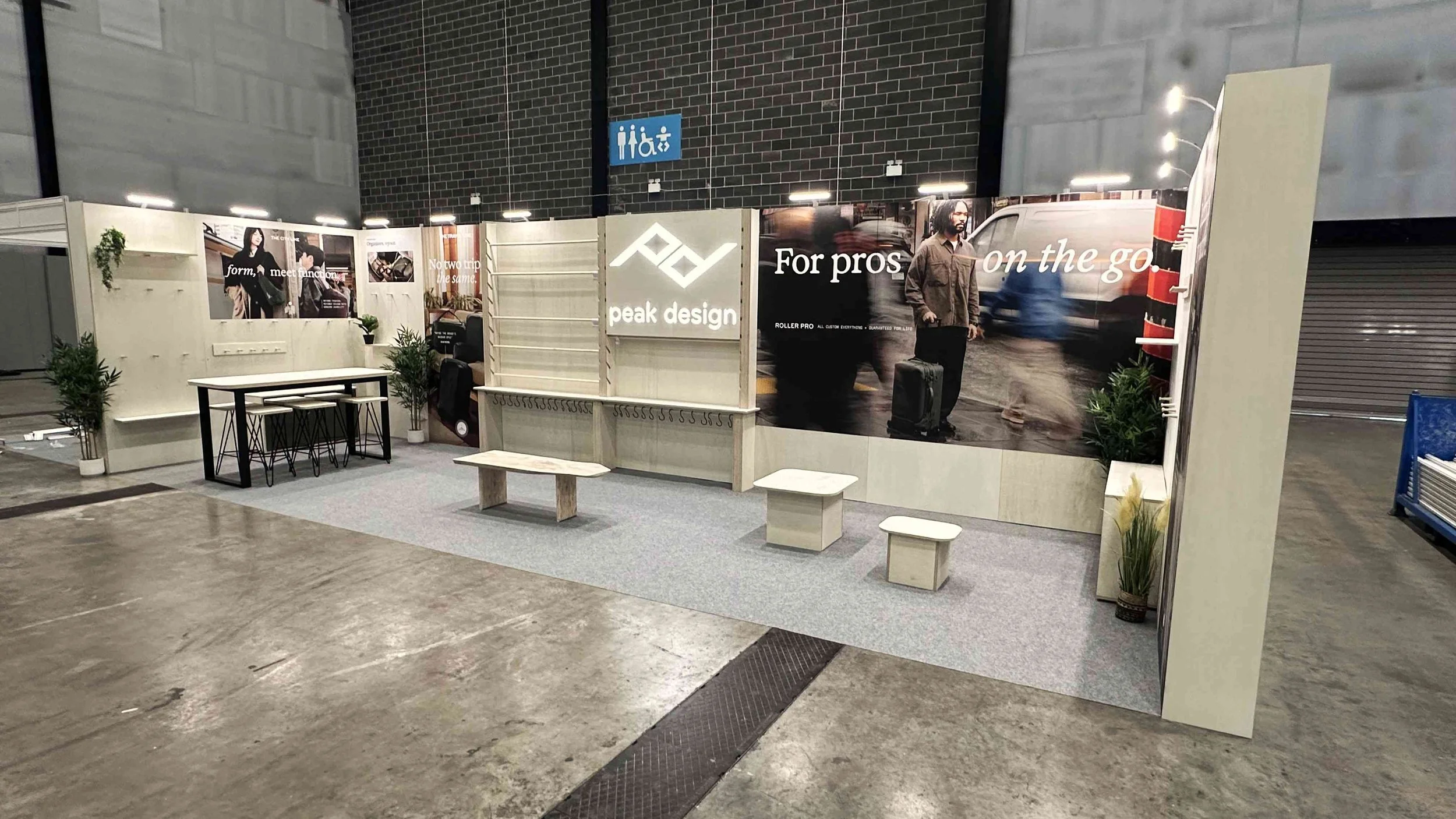 Peak Design trade show stand with meeting table, branded graphics and product display walls